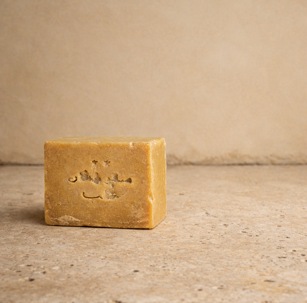 Bar of aleppo soap with a logo on a travertine surface and lime plaster background