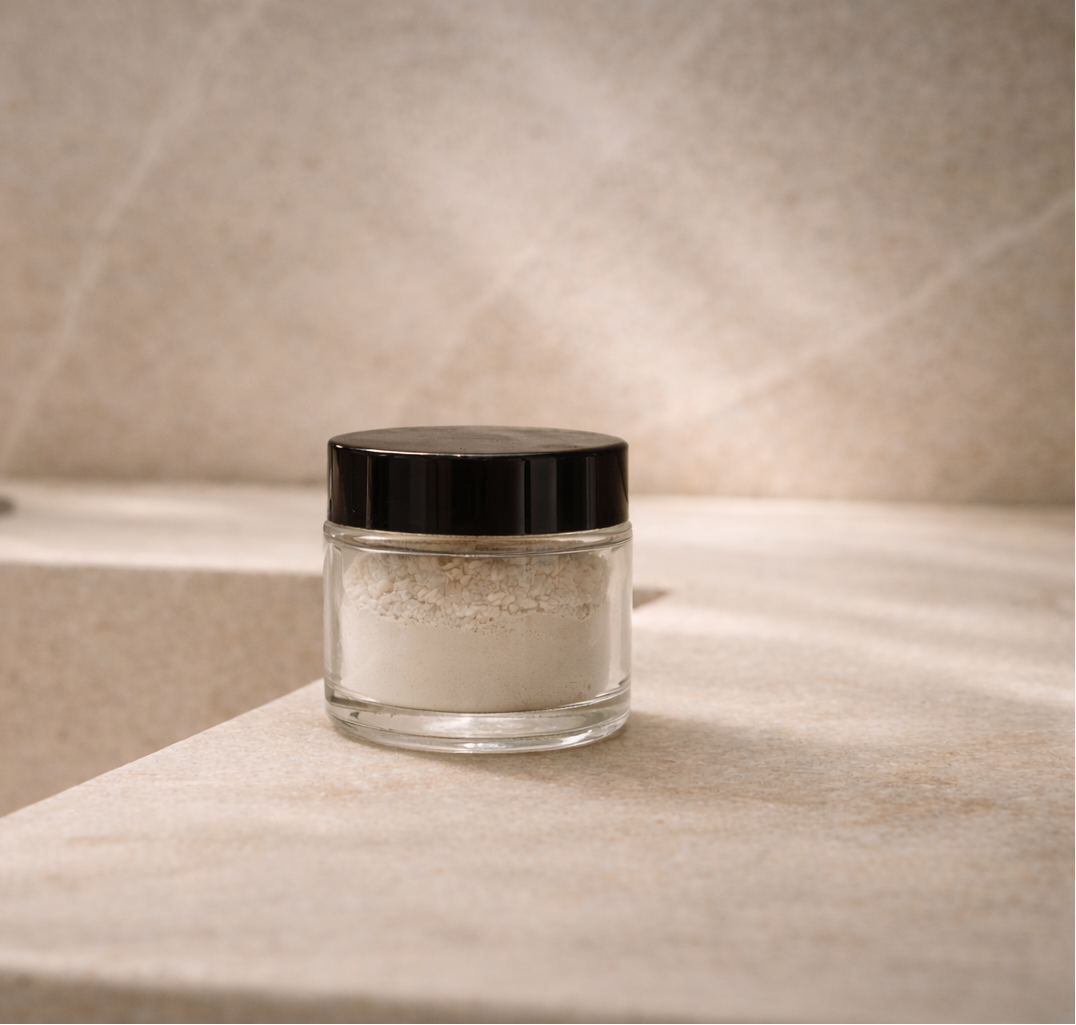 Jar of toothpowder on a bathroom counter with a faucet in the background