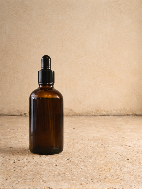 Amber glass dropper bottle on a textured surface with a neutral background